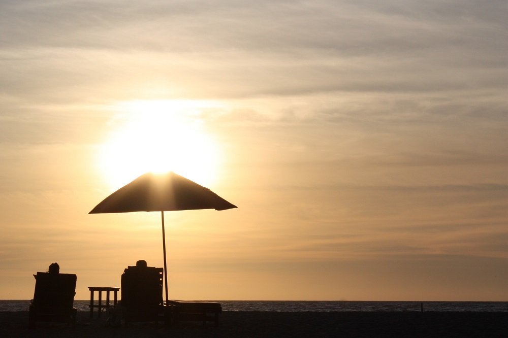 casal sentados em cadeira de praia olhando o pôr do sol